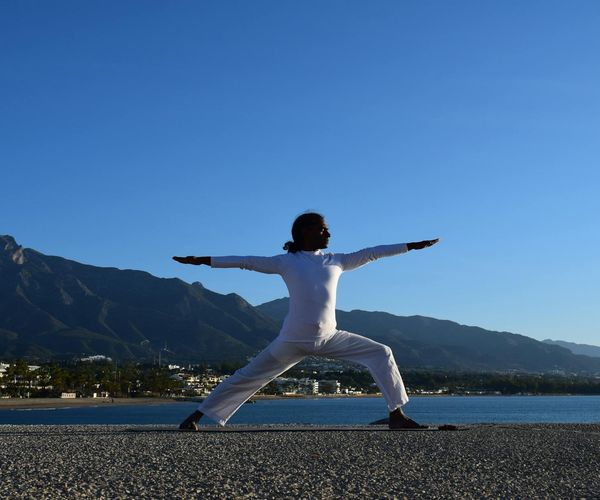 Silhouette of a person in a warrior yoga pose during sunrise.